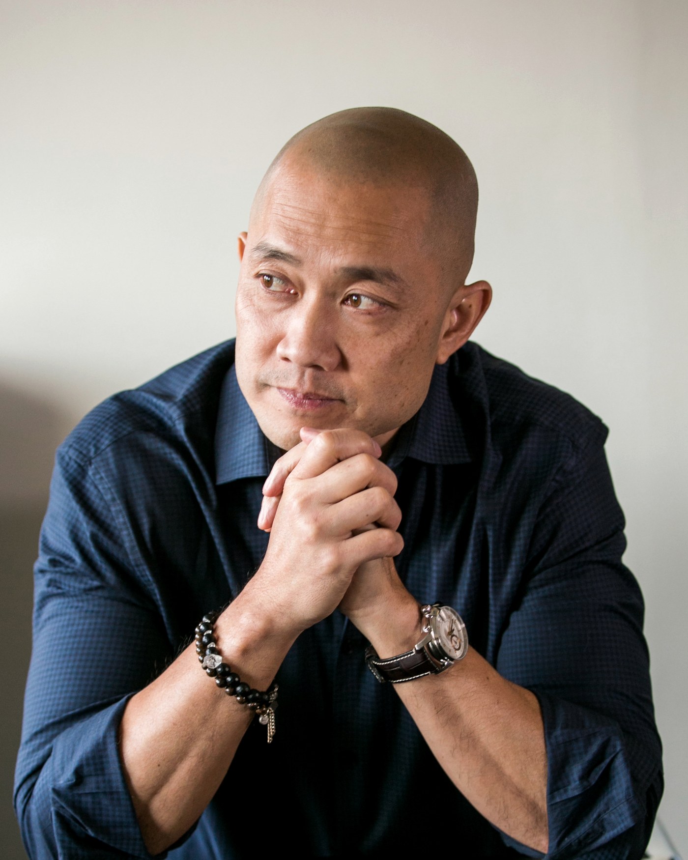Wei Houng, seated, hands steepled, listening.